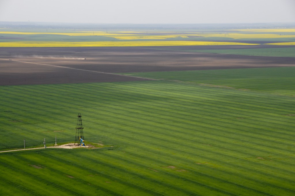 aerial view of single oil well in green crops field